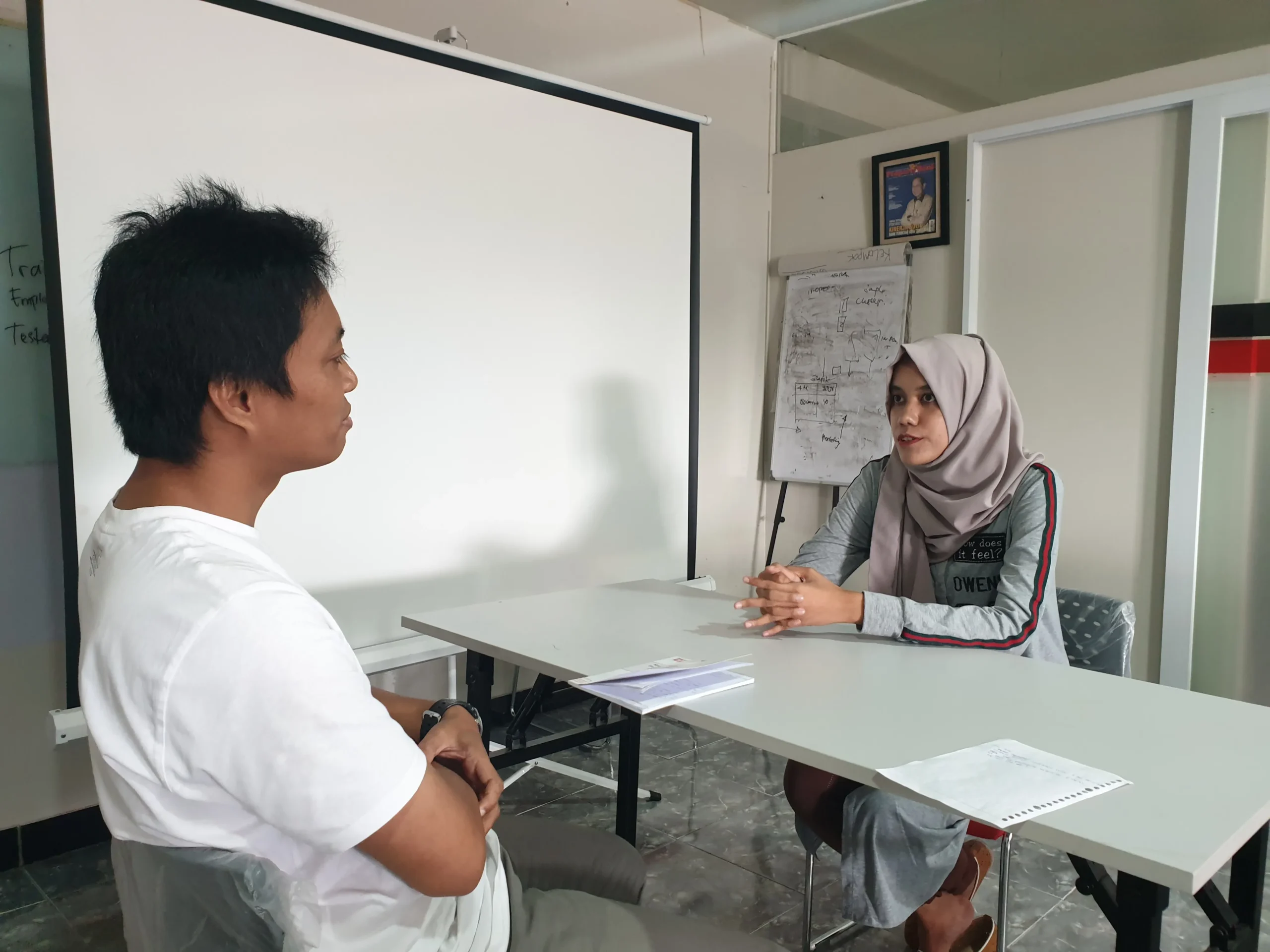 Seorang pelajar atau profesional muda fokus menulis esai aplikasi di depan laptop dalam lingkungan belajar yang bersih dan cerah