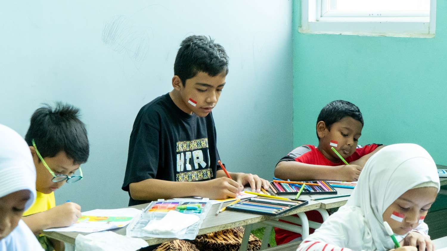 Anak dengan wajah sangat bahagia dan bangga sedang asyik memegang kuas dan mewarnai karya lukisnya dengan penuh warna